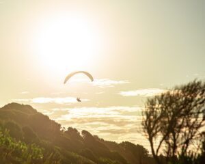 Gleitschirmfliegen bei Sonnenuntergang in einem Tal. Outdoor-Abenteuer.